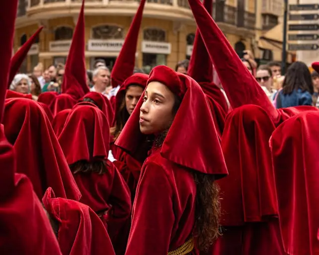 Tradizioni Pasqua Italia: processione della Settimana Santa con confratelli in abiti cerimoniali rossi durante riti pasquali