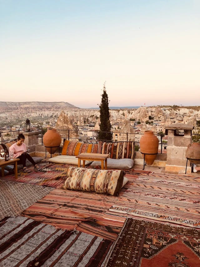 Terrazza panoramica tradizionale in Cappadocia con tappeti locali e vista mozzafiato all'alba, esempio perfetto di viaggio immersivo e esperienza autentica lontano dal turismo di massa