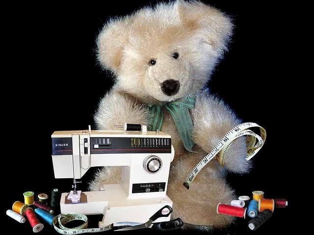 Orsetto di peluche con macchina da cucire Singer e fili colorati - simbolo della moda sostenibile e artigianale 2025